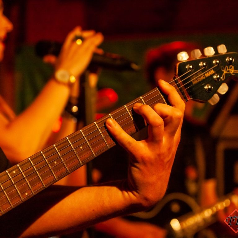 Tim Theissen Eventfotograf Gitarrenspieler bei einem Live Auftritt. Im Hintergrund ist die Sängerin zu entdecken