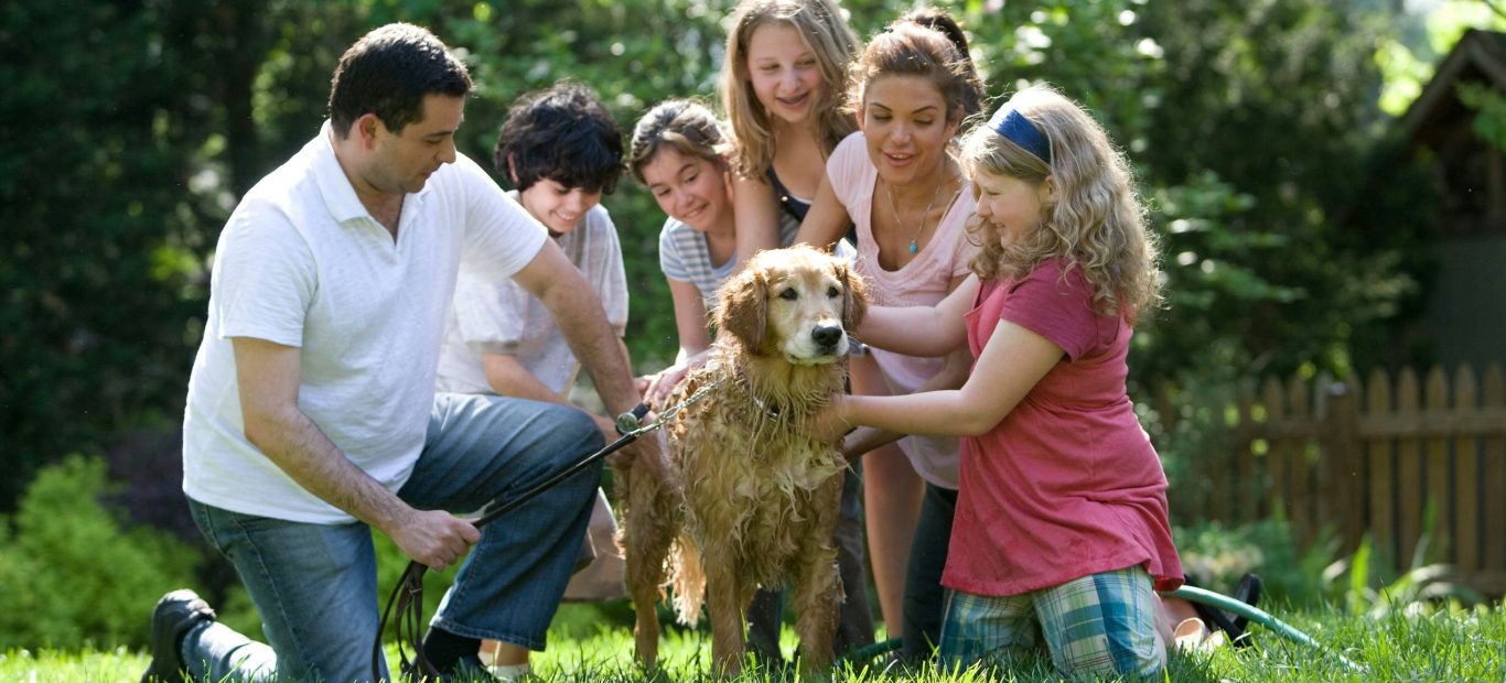 Familienbild Familie wäscht zusammen den Hund im Garten
