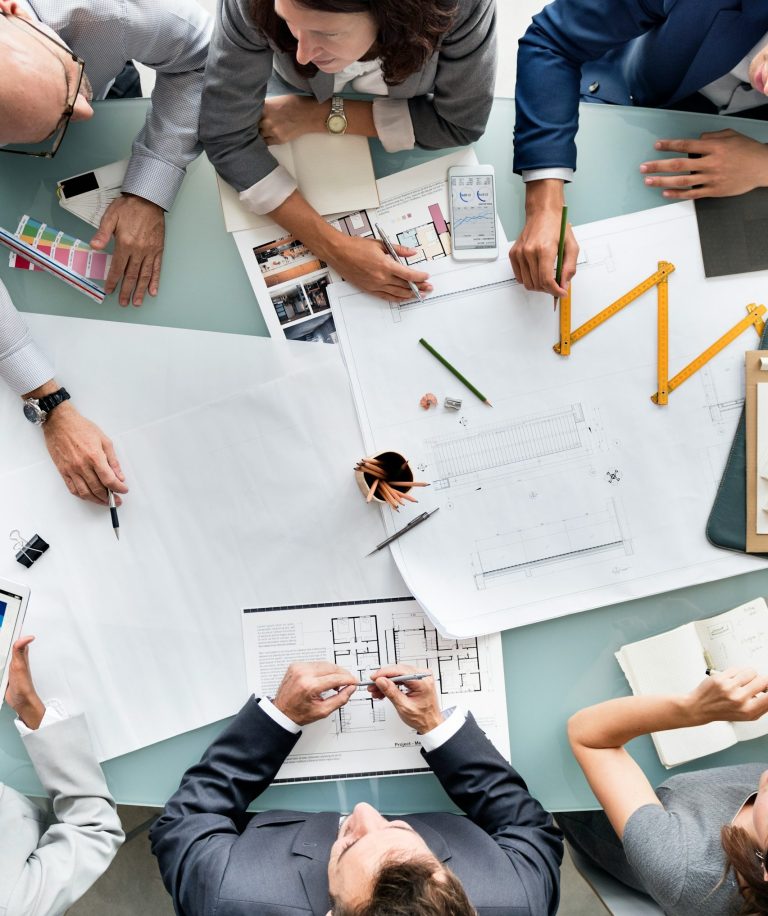 Planung ist alles Menschen sitzen vor Plänen am Schrietisch und diskutieren