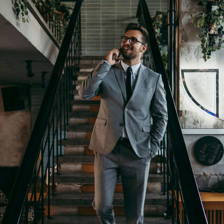 Businessportraits Mann im grauen Anzug telefoniert und geht Treppe hinunter