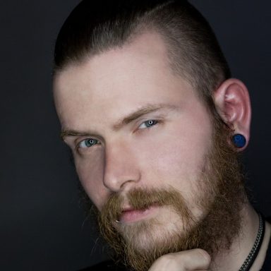 Mann mit Bart, kurzen Haaren und blauen Augen, sieht direkt in die Kamera.