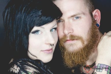 Junges Paar mit dunklen Haaren und Bart, nah zusammen posierend.