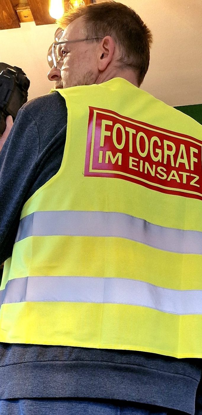 Fotograf im Einsatz Mann mit gelber Weste und Aufschrift "Fotograf im Einsatz"