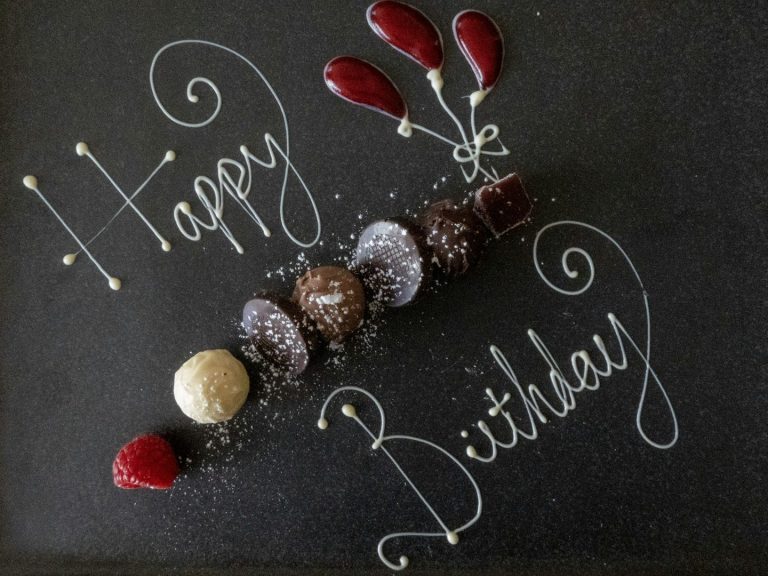 Schokoladentrüffel und Beeren mit "Happy Birthday" in Schrift aus Zucker.