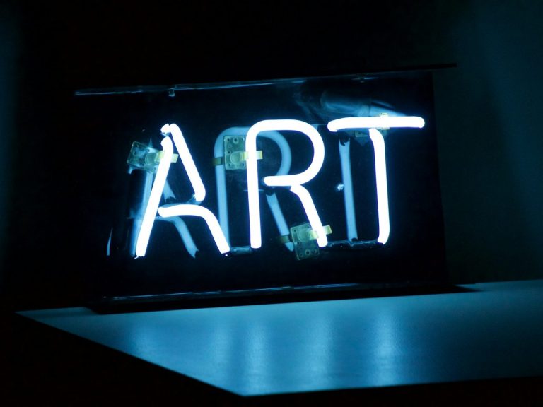 Neonlicht in der Form des Wortes "ART" auf einem dunklen Hintergrund.