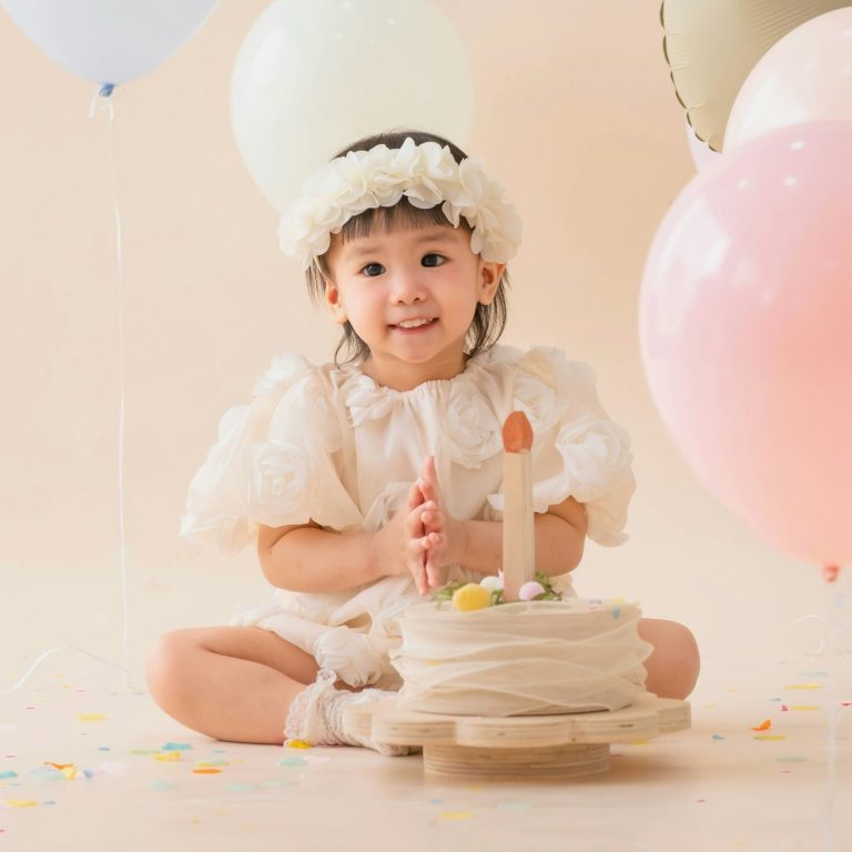 Erster Geburtstag Mädchen im weißen Kostüm sitzt auf Boden