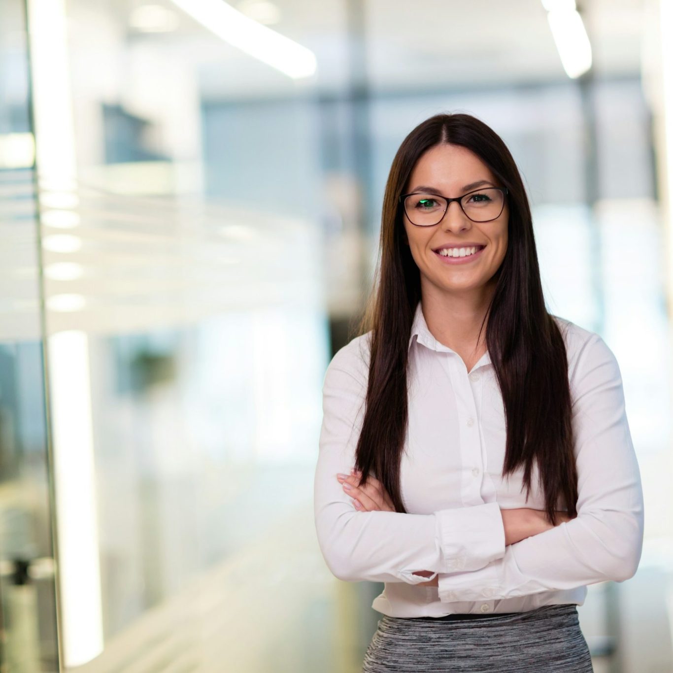 Mitarbeiterfotos Frau mit Brille und langen schwarzen Haaren trägt ein Business Outfit und lächelt in die Kamera