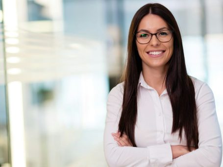 Team Mitglieder Frau mit Brille und langen Harren in weißem Hemd lächelt in Kamera