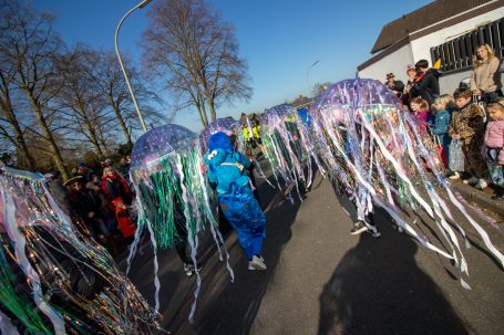 Bunte Quallenkostüme bei einer Parade, umgeben von Zuschauern.