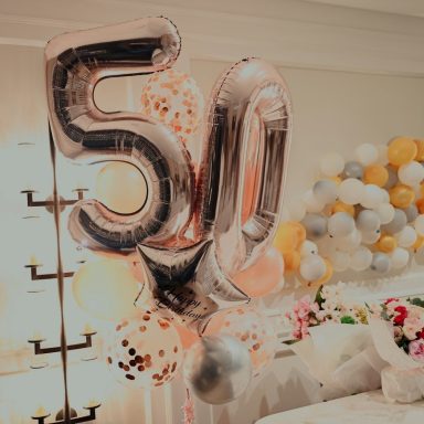 Silberne Luftballons mit der Zahl 50 und bunten Dekorationen im Hintergrund.
