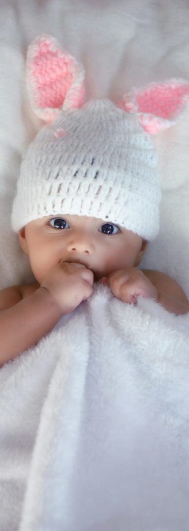 Shooting Baby mit Haasenmütze liegt unter Decke