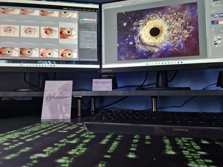 Zwei Computerbildschirme mit kreativen Designs und darunter eine Tastatur mit grünen Tasten.
