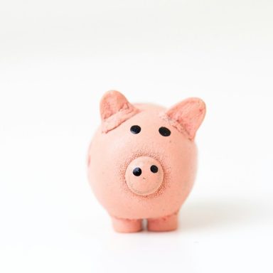 Schweinsförmige Sparschwein aus Keramik in rosa mit schwarzen Augen.