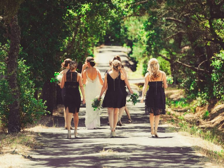 Gruppe von Frauen in schwarzen Kleidern, die auf einen Weg zu einer Zeremonie gehen.