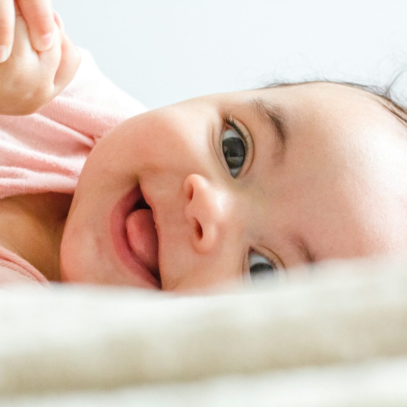 Newborn Shooting Baby liegt auf Decke und lacht.