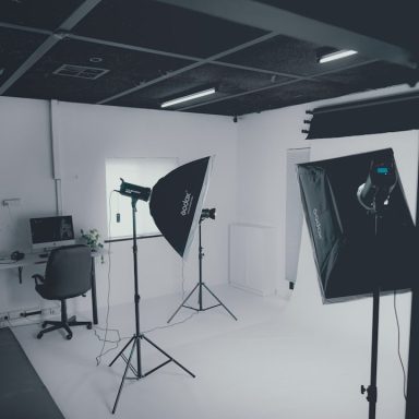 Ein helles Fotostudio mit Beleuchtung, Stativ und Arbeitsplatz in neutralem Design.