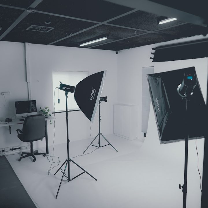 Fotostudio mit Stative, Kamera-Equipment und Schreibtisch in einem hellen Raum.