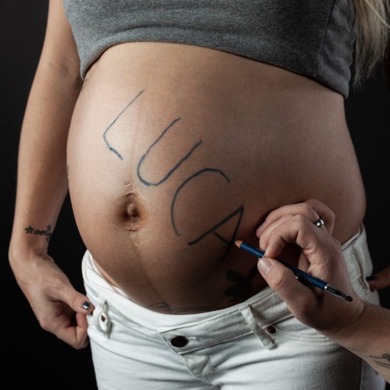 Babybauch Shooting Eine schwangere Frau die "Luca" auf ihren Bauch schreibt