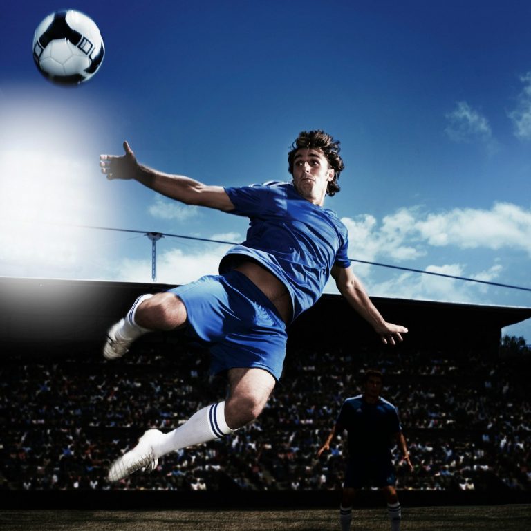 Tim Theissen Vereinsfotograf Fußballspieler springt und versucht Ball zu treffen. Blaues Trikot