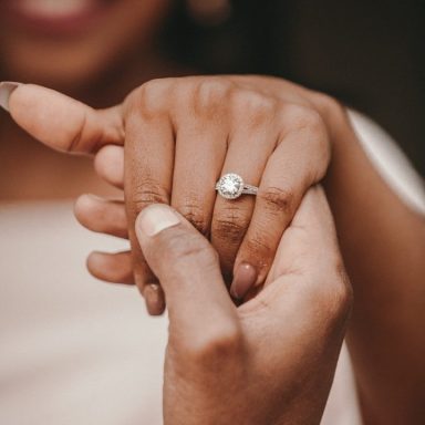 Hände mit einem Verlobungsring an einem Finger, symbolisieren Liebe und Engagement.