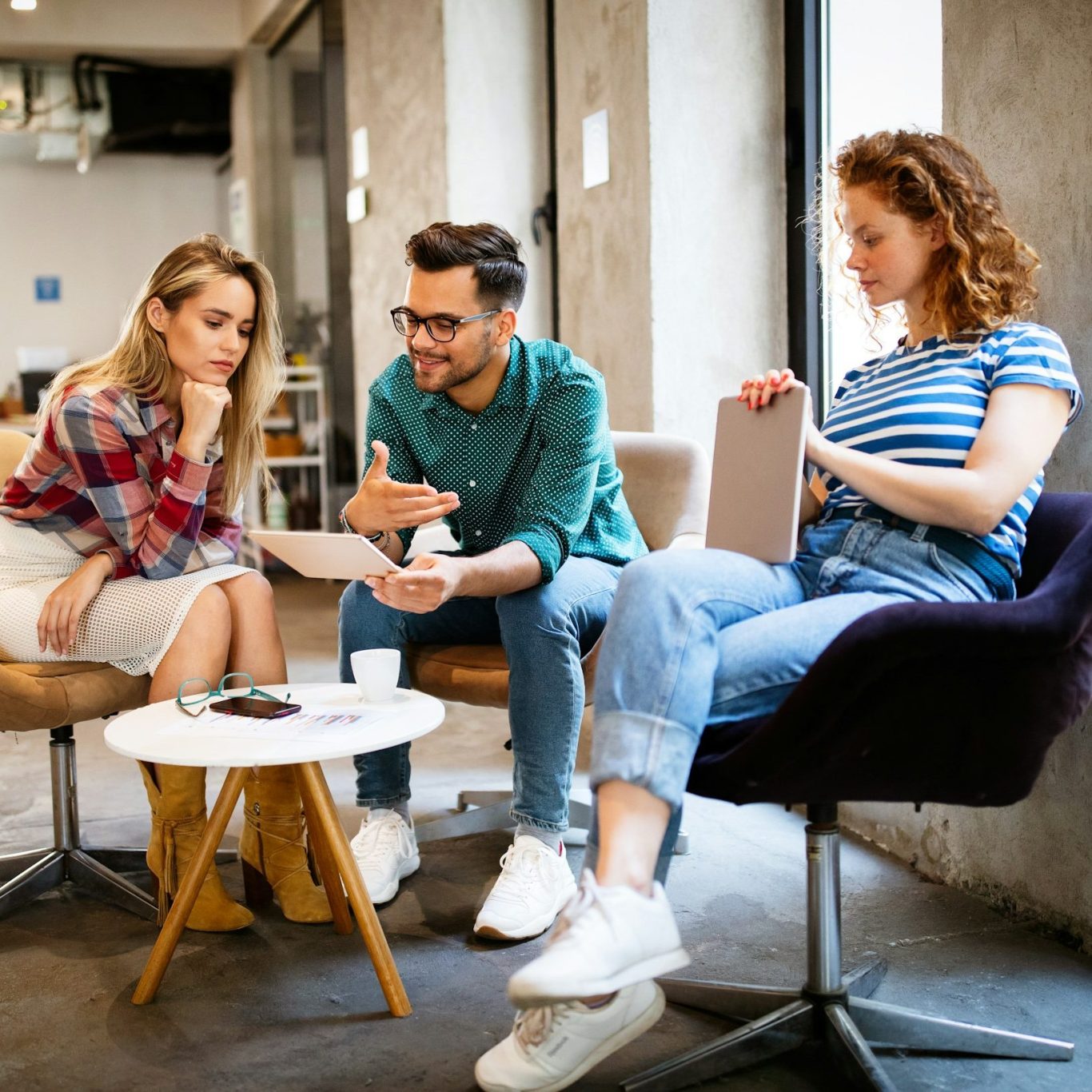 Content Shooting Ein Team aus zwei Frauen und einem Mannsitzen an einem Tisch und halten ein Meeting ab