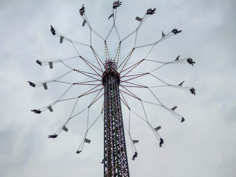 Freizeitpark-Attraktion mit Fahrgästen, die an langen Armen rotieren.
