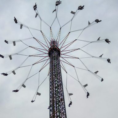 Fahrgeschäft mit schwingenden Sitzen, die an einem hohen Turm befestigt sind.