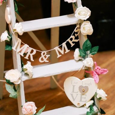 Eine Holzleiter geschmückt mit Blumen und einem "MR & MRS" Banner.