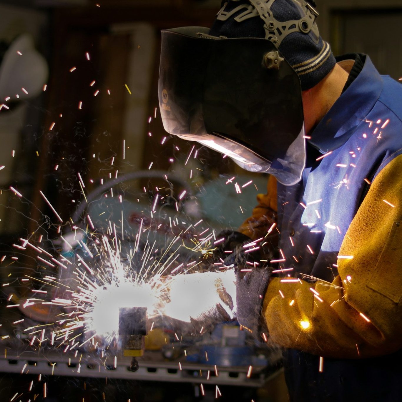Unetrnehmensreportage Arbeiter in Schutzbekleidung schweißt Metall. Funken sprühen
