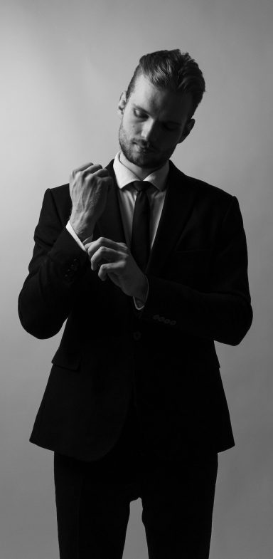 Linkedin Portraits Mann mit Anzug richtet sein Hemd in Schwarz Weiß