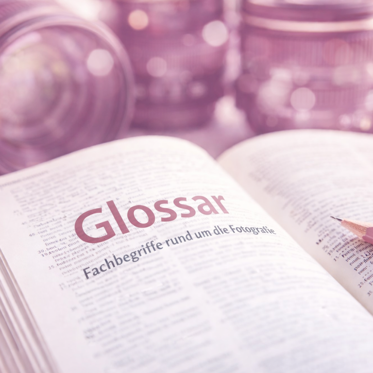 Glossar mit Fachbegriffen, umgeben von verschwommenen Gläsern im Hintergrund.